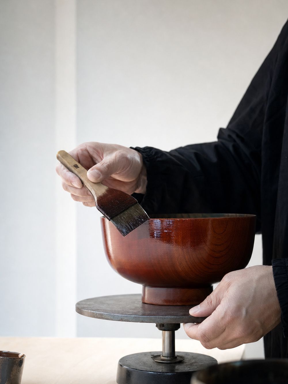 A craftsperson applying urushi lacquer to a wooden bowl